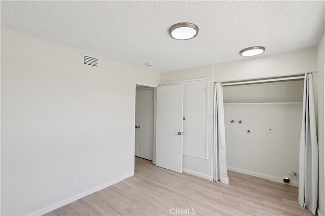 1122 W Galway St, Rialto, CA 92377 - unfurnished bedroom with a textured ceiling, light wood-type flooring, and two closets