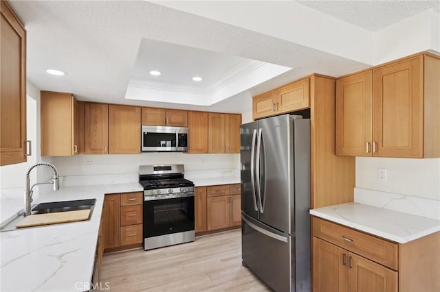 1122 W Galway St, Rialto, CA 92377 - kitchen featuring stainless steel appliances, light stone countertops, a raised ceiling, light wood-style flooring, and a textured ceiling