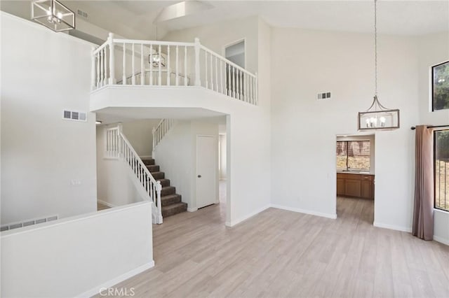 1122 W Galway St, Rialto, CA 92377 - unfurnished living room featuring a towering ceiling, a chandelier, wood finished floors, and stairway
