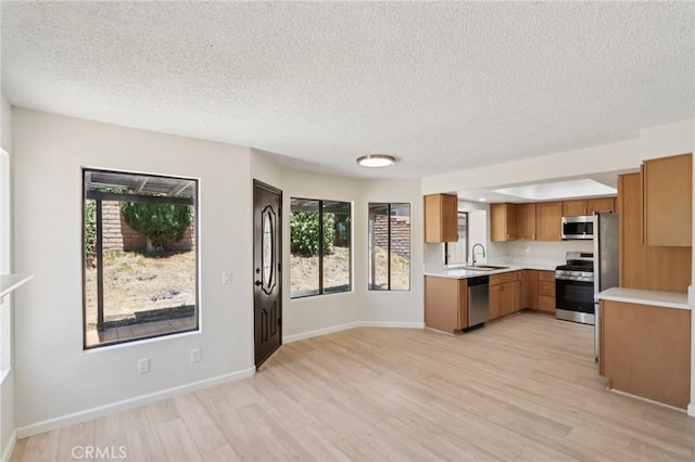 1122 W Galway St, Rialto, CA 92377 - kitchen with stainless steel appliances, light countertops, brown cabinetry, light wood-style floors, and a textured ceiling