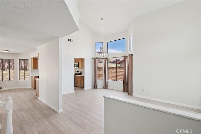 1122 W Galway St, Rialto, CA 92377 - hall featuring a chandelier, light wood-type flooring, and a towering ceiling