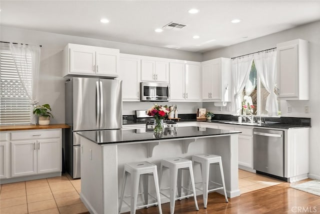 3192 Sawyers Bar Ln, Chico, CA 95973 - kitchen featuring appliances with stainless steel finishes, white cabinets, a kitchen breakfast bar, dark countertops, and a center island