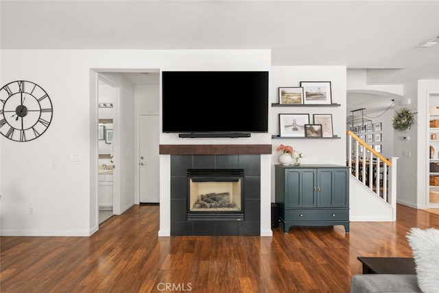 3192 Sawyers Bar Ln, Chico, CA 95973 - living area with stairs, dark wood-style floors, a tiled fireplace, and arched walkways