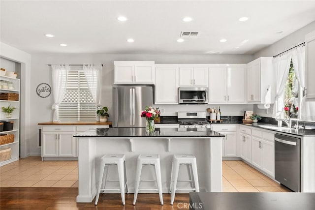 3192 Sawyers Bar Ln, Chico, CA 95973 - kitchen with appliances with stainless steel finishes, a kitchen island, white cabinets, a breakfast bar area, and recessed lighting