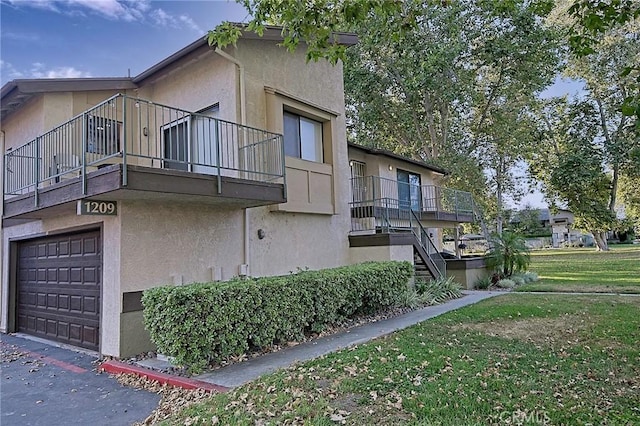 1209 Edwards St Unit 56, Redlands, CA 92374 - view of side of property featuring a balcony, stucco siding, an attached garage, a lawn, and stairway
