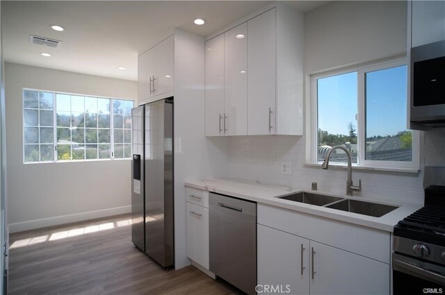1020 Lantana Dr, Los Angeles, CA 90042 - kitchen featuring stainless steel appliances, decorative backsplash, white cabinetry, recessed lighting, and light wood-type flooring