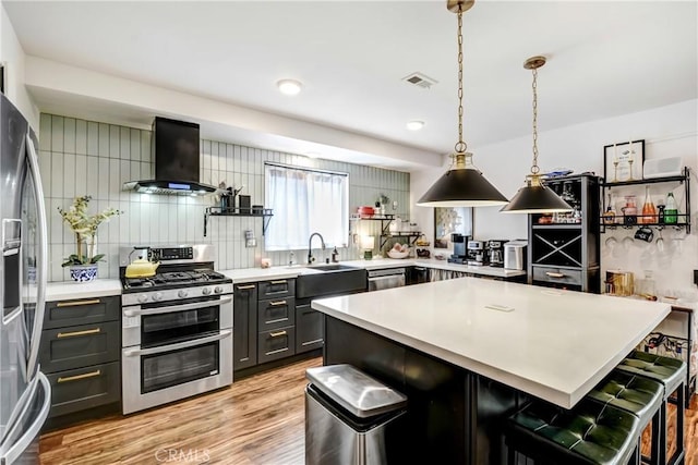 458 Termino Ave, Corona, CA 92879 - kitchen featuring appliances with stainless steel finishes, wall chimney exhaust hood, light countertops, a breakfast bar, and recessed lighting