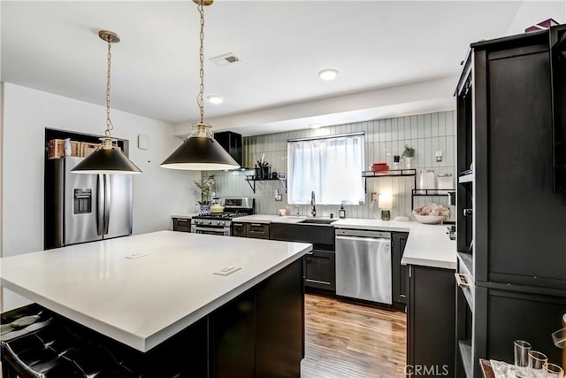 458 Termino Ave, Corona, CA 92879 - kitchen featuring appliances with stainless steel finishes, light countertops, tasteful backsplash, light wood-style floors, and a center island