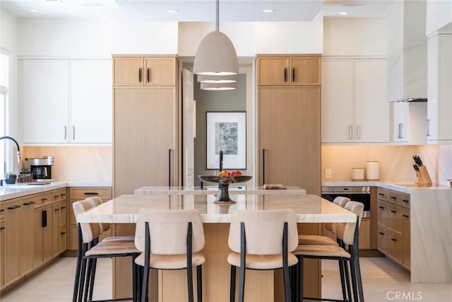 4 Ebony Glade, Laguna Niguel, CA 92677 - kitchen featuring wall chimney range hood, a breakfast bar area, a center island, decorative light fixtures, and stainless steel oven