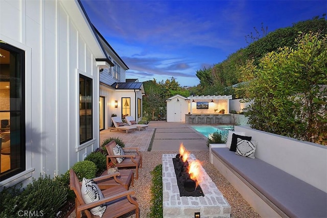 2001 Port Ramsgate Pl, Newport Beach, CA 92660 - patio terrace at dusk featuring a patio, an outdoor living space with a fire pit, and an outdoor pool