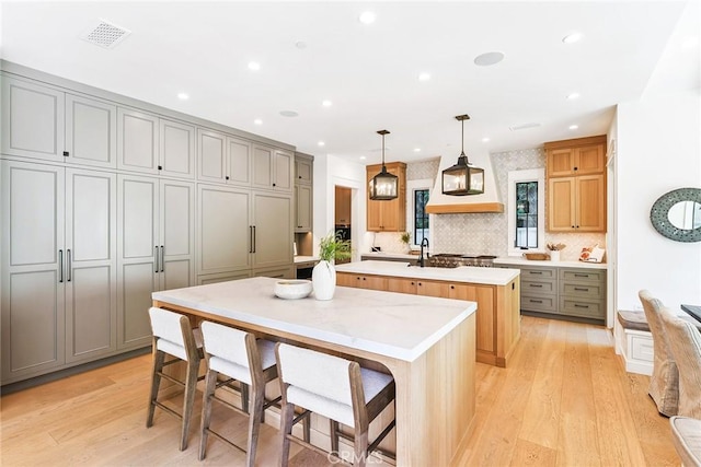 2001 Port Ramsgate Pl, Newport Beach, CA 92660 - kitchen featuring a kitchen island with sink, gray cabinetry, light wood-style floors, tasteful backsplash, and recessed lighting