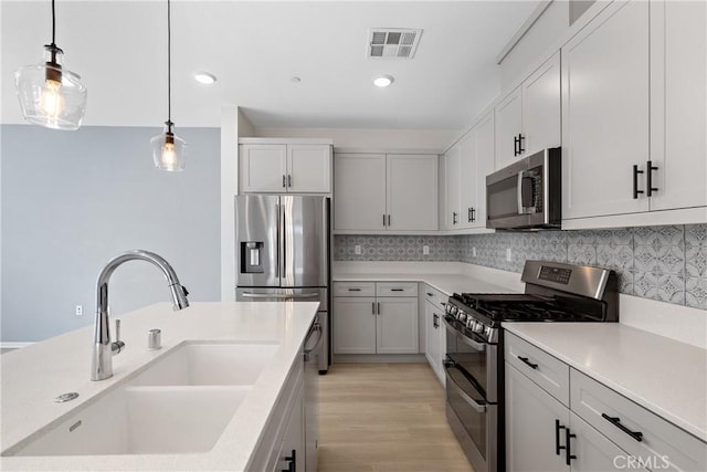 35115 Vine Pl, Fallbrook, CA 92028 - kitchen with stainless steel appliances, pendant lighting, light wood finished floors, backsplash, and light countertops