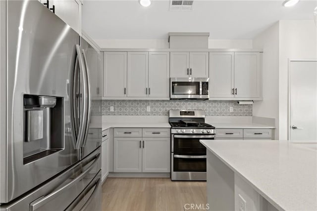 35115 Vine Pl, Fallbrook, CA 92028 - kitchen featuring appliances with stainless steel finishes, light countertops, light wood-style flooring, and decorative backsplash