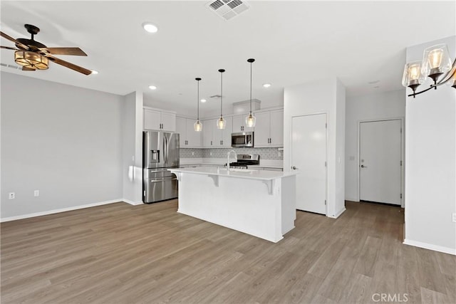 35115 Vine Pl, Fallbrook, CA 92028 - kitchen with stainless steel appliances, light countertops, decorative backsplash, light wood finished floors, and a kitchen breakfast bar