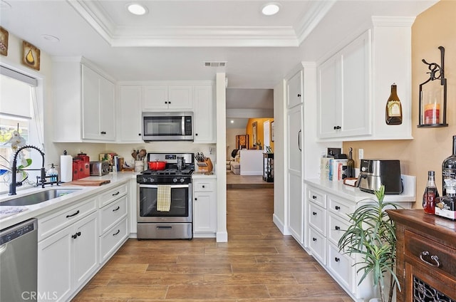 10 Glenhurst Unit 37, Irvine, CA 92604 - kitchen with stainless steel appliances, a tray ceiling, light countertops, white cabinetry, and recessed lighting