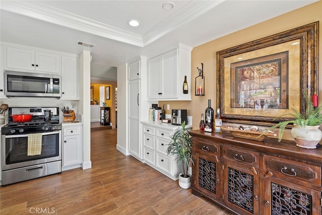 10 Glenhurst Unit 37, Irvine, CA 92604 - kitchen featuring appliances with stainless steel finishes, a tray ceiling, white cabinetry, wood finished floors, and recessed lighting