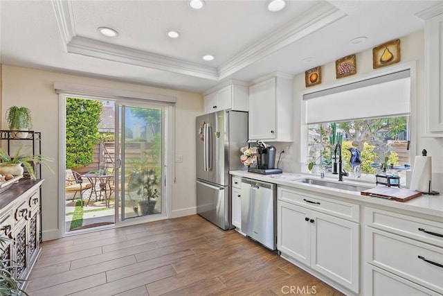 10 Glenhurst Unit 37, Irvine, CA 92604 - kitchen with appliances with stainless steel finishes, ornamental molding, a raised ceiling, white cabinetry, and light countertops