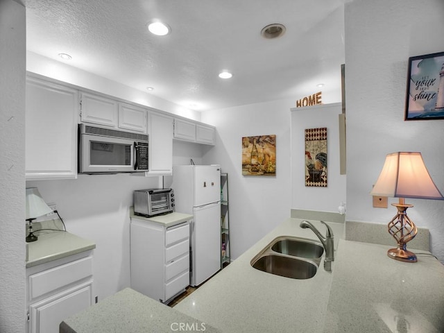11410 Dolan Unit 328, Downey, CA 90241 - kitchen featuring stainless steel microwave, freestanding refrigerator, recessed lighting, light stone counters, and white cabinetry