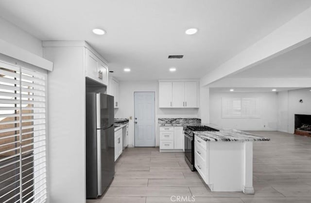 7915 Helena Ave, Riverside, CA 92504 - kitchen with freestanding refrigerator, range with gas cooktop, light stone countertops, white cabinetry, and recessed lighting