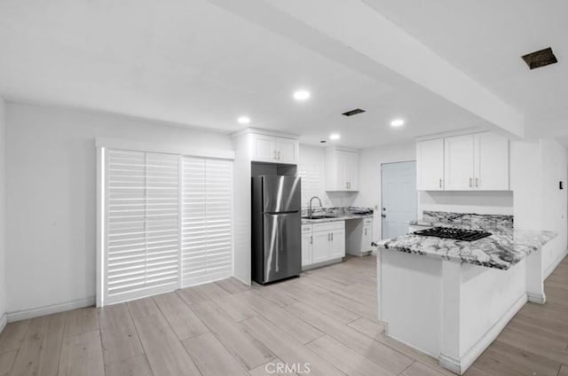 7915 Helena Ave, Riverside, CA 92504 - kitchen featuring freestanding refrigerator, black stovetop, a peninsula, light stone countertops, and white cabinets