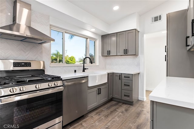 853 N Jasmine Ave, Ontario, CA 91762 - kitchen with appliances with stainless steel finishes, wall chimney range hood, gray cabinetry, wood finished floors, and recessed lighting