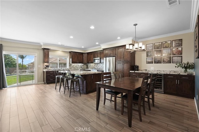 1018 W 15th St, Upland, CA 91786 - dining space with beverage cooler, a chandelier, crown molding, light wood finished floors, and recessed lighting