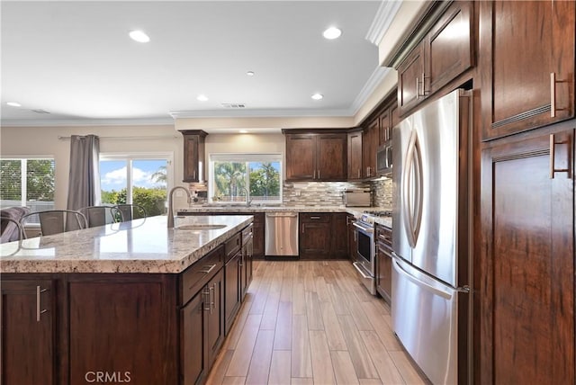 1018 W 15th St, Upland, CA 91786 - kitchen with stainless steel appliances, light stone counters, dark brown cabinets, a center island with sink, and decorative backsplash