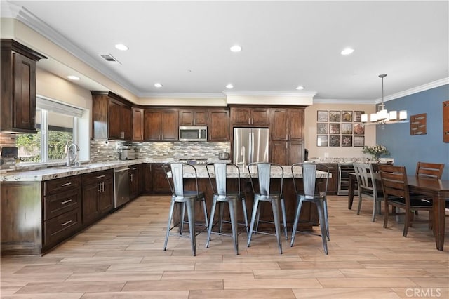 1018 W 15th St, Upland, CA 91786 - kitchen featuring appliances with stainless steel finishes, dark brown cabinets, a chandelier, a kitchen breakfast bar, and light wood-type flooring