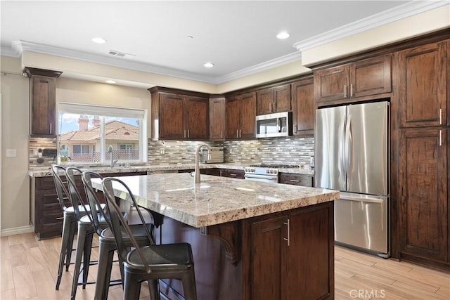 1018 W 15th St, Upland, CA 91786 - kitchen with appliances with stainless steel finishes, light stone counters, dark brown cabinets, a kitchen bar, and ornamental molding