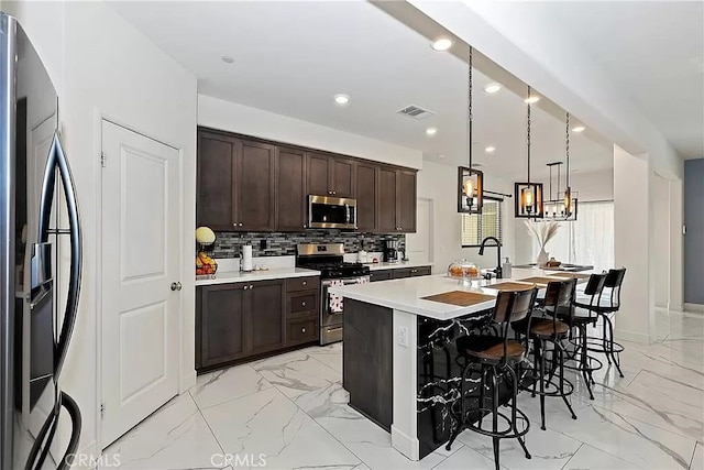 12465 Gramercy Ln, Victorville, CA 92392 - kitchen featuring appliances with stainless steel finishes, light marble finish floors, dark brown cabinets, light countertops, and recessed lighting