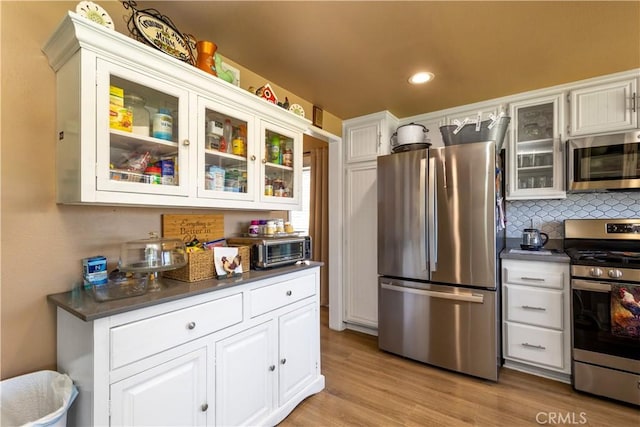28219 Langside Ave, Canyon Country, CA 91351 - kitchen featuring appliances with stainless steel finishes, dark countertops, glass insert cabinets, white cabinets, and recessed lighting