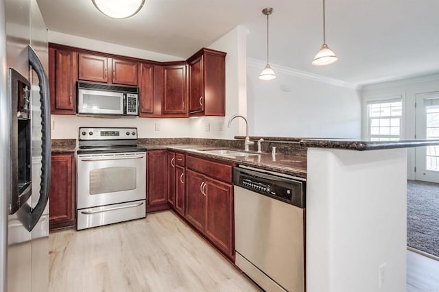 506 Canyon Dr Unit 70, Oceanside, CA 92054 - kitchen with stainless steel appliances, a peninsula, light wood-type flooring, dark stone countertops, and ornamental molding