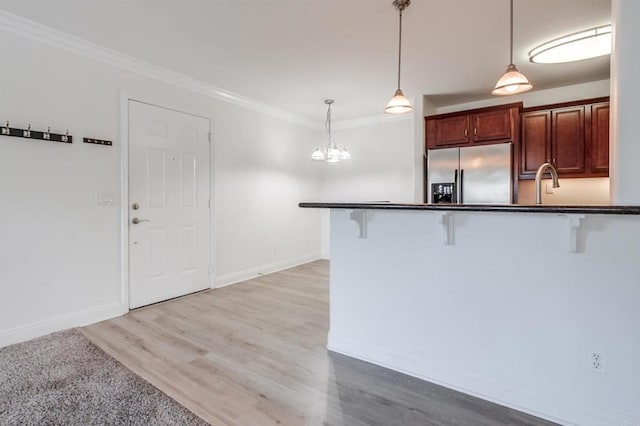 506 Canyon Dr Unit 70, Oceanside, CA 92054 - kitchen with stainless steel fridge with ice dispenser, a breakfast bar area, dark countertops, hanging light fixtures, and ornamental molding