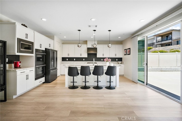 28508 Daybreak Way, Saugus, CA 91350 - kitchen featuring high end fridge, stainless steel microwave, a kitchen bar, under cabinet range hood, and light countertops