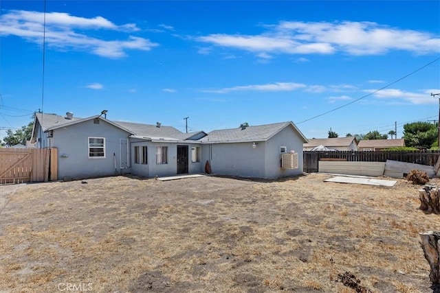24976 7th St, San Bernardino, CA 92410 - back of property featuring a fenced backyard, stucco siding, and a gate