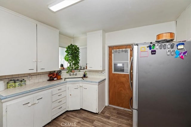 24976 7th St, San Bernardino, CA 92410 - kitchen featuring freestanding refrigerator, tile counters, white cabinetry, backsplash, and dark wood-style floors