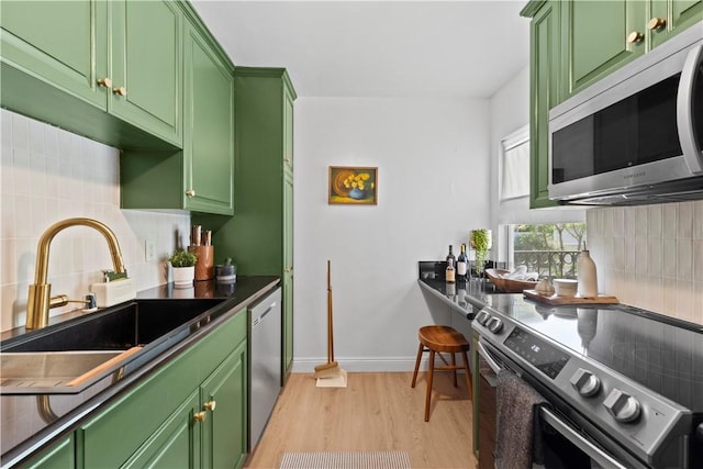 625 N Flores St Unit 202, West Hollywood, CA 90048 - kitchen with stainless steel appliances, green cabinetry, light wood-style flooring, and tasteful backsplash