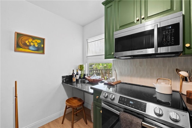625 N Flores St Unit 202, West Hollywood, CA 90048 - kitchen featuring stainless steel appliances, green cabinetry, decorative backsplash, and light wood-style floors
