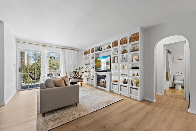 625 N Flores St Unit 202, West Hollywood, CA 90048 - living area with wood finished floors, arched walkways, a glass covered fireplace, and built in features