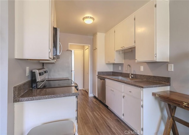 12200 Montecito Rd Unit D320, Seal Beach, CA 90740 - kitchen with appliances with stainless steel finishes, dark countertops, wood finished floors, and white cabinetry