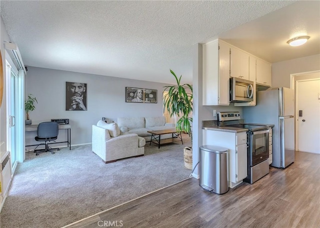 12200 Montecito Rd Unit D320, Seal Beach, CA 90740 - kitchen with appliances with stainless steel finishes, white cabinets, wood finished floors, a textured ceiling, and open floor plan