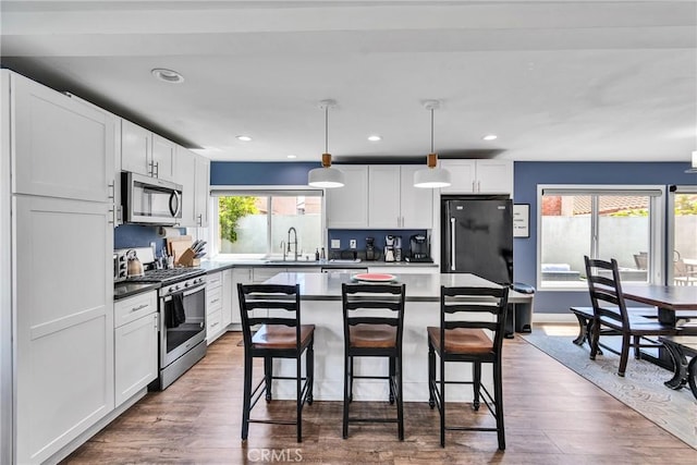 3609 S Parton St, Santa Ana, CA 92707 - kitchen with stainless steel appliances, a breakfast bar area, wood finished floors, white cabinetry, and recessed lighting