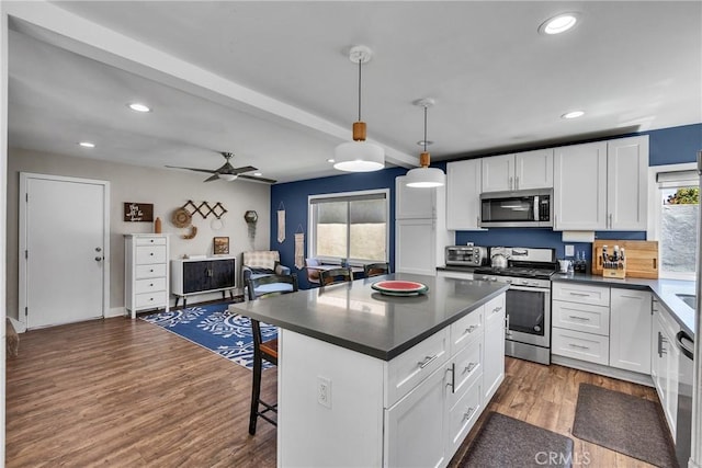 3609 S Parton St, Santa Ana, CA 92707 - kitchen with appliances with stainless steel finishes, dark countertops, recessed lighting, white cabinets, and a kitchen breakfast bar