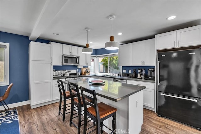 3609 S Parton St, Santa Ana, CA 92707 - kitchen with stainless steel appliances, white cabinets, wood finished floors, recessed lighting, and beam ceiling