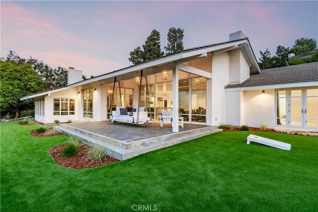16 Roadrunner Rd, Rolling Hills, CA 90274 - back of house at dusk featuring a chimney, a yard, french doors, and a patio