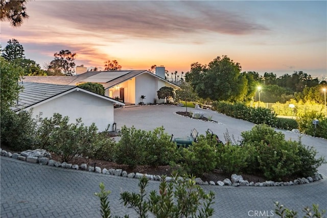 16 Roadrunner Rd, Rolling Hills, CA 90274 - back of property at dusk featuring roof mounted solar panels, a chimney, and stucco siding