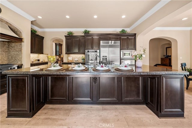 19668 Three Oaks Ln, Walnut, CA 91789 - kitchen with built in appliances, arched walkways, a large island with sink, dark stone counters, and backsplash