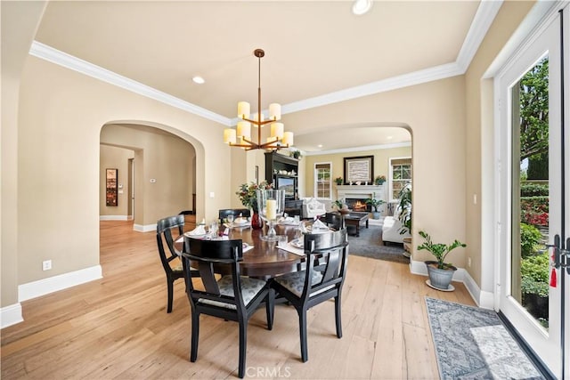 19668 Three Oaks Ln, Walnut, CA 91789 - dining area with a chandelier, a warm lit fireplace, arched walkways, ornamental molding, and light wood-type flooring