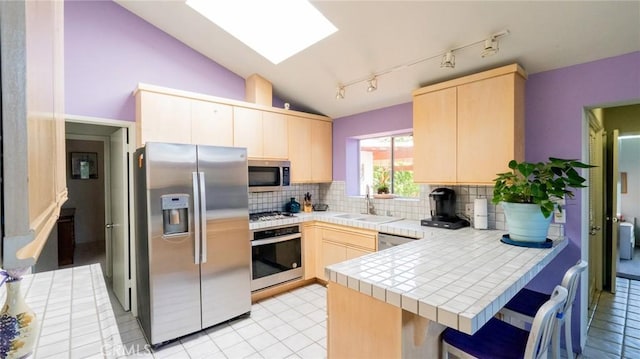 3456 Veteran Ave, Los Angeles, CA 90034 - kitchen featuring appliances with stainless steel finishes, light brown cabinetry, a peninsula, tile counters, and vaulted ceiling