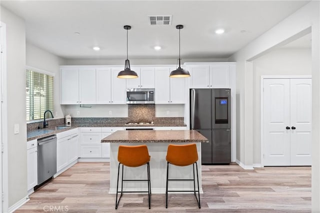 16004 Huckleberry Ave, Chino, CA 91708 - kitchen with stainless steel appliances, light wood finished floors, a center island, white cabinetry, and recessed lighting